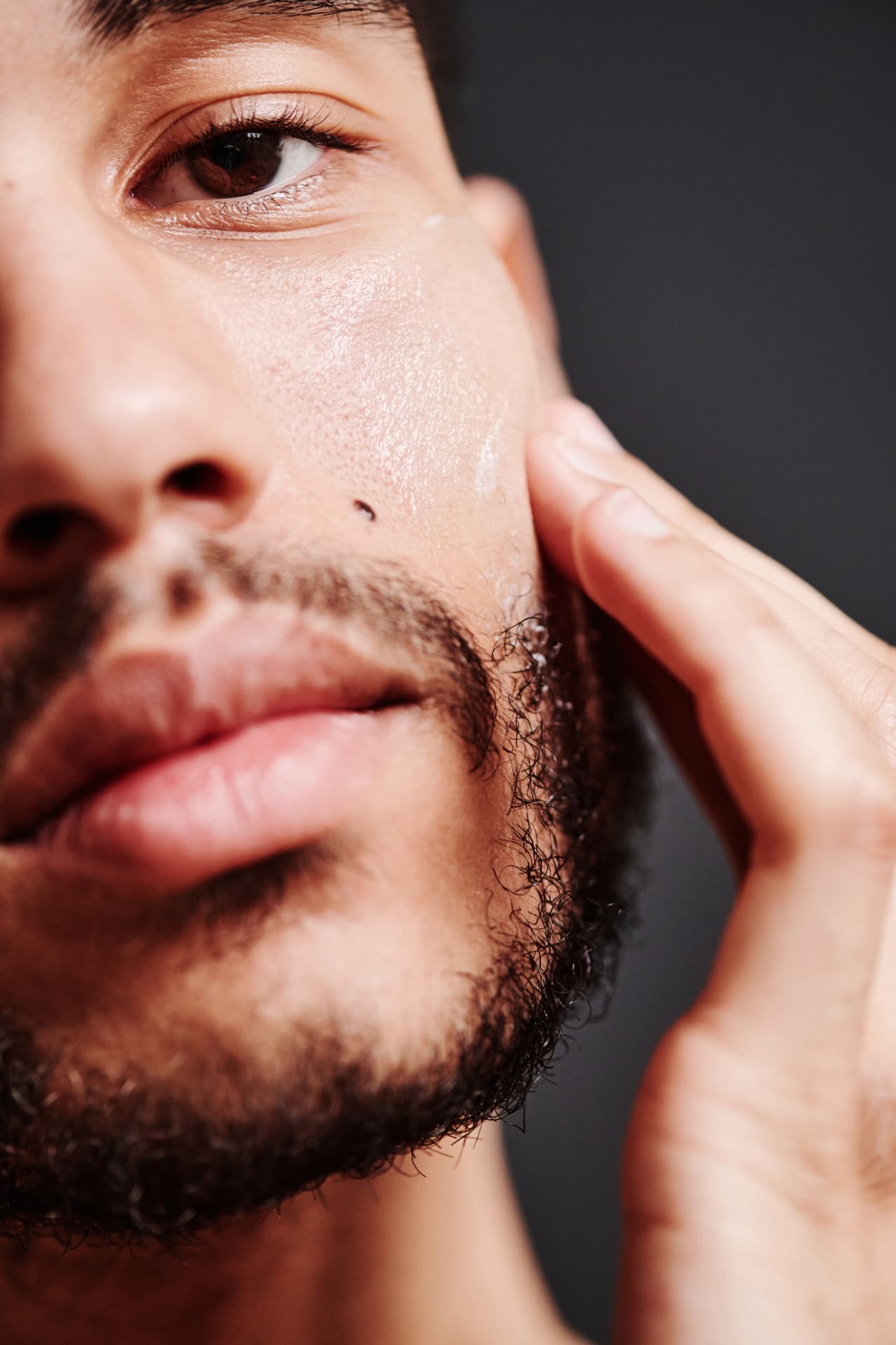 Close-up of a man applying compounded skin cream along his cheek