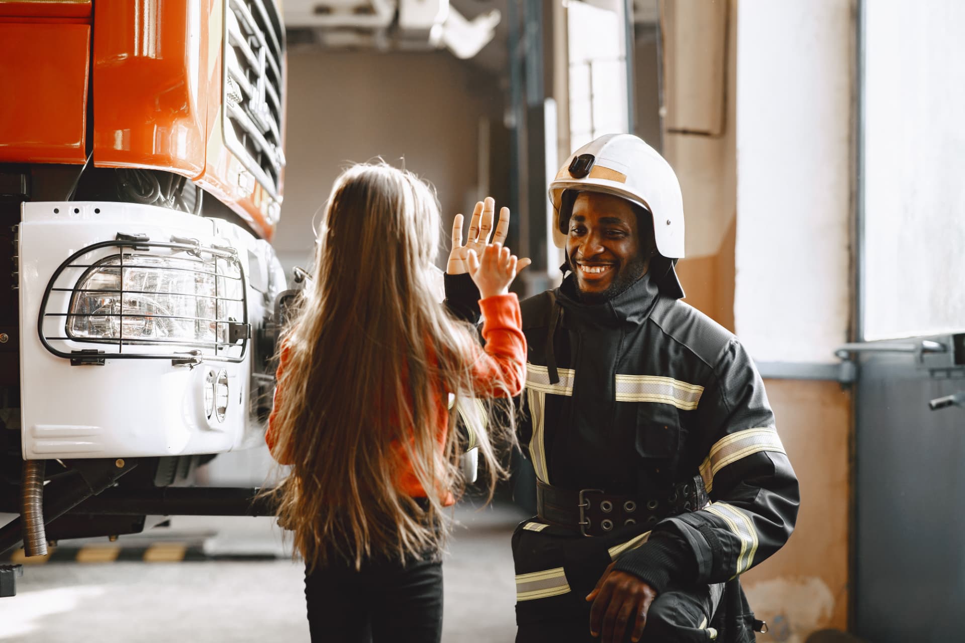 Firefighter high-fiving a young girl at the station